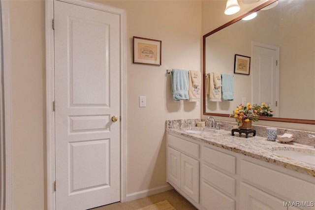 full bathroom featuring a sink, baseboards, and double vanity