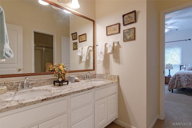 full bath with baseboards, double vanity, a sink, and connected bathroom