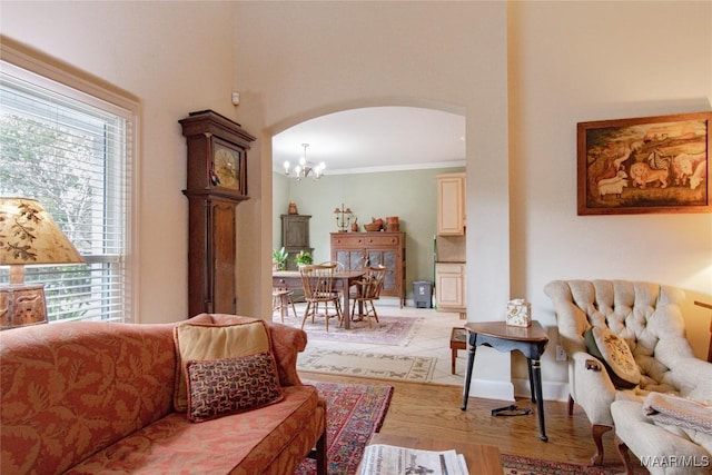 living room with arched walkways, light wood-type flooring, a chandelier, and crown molding