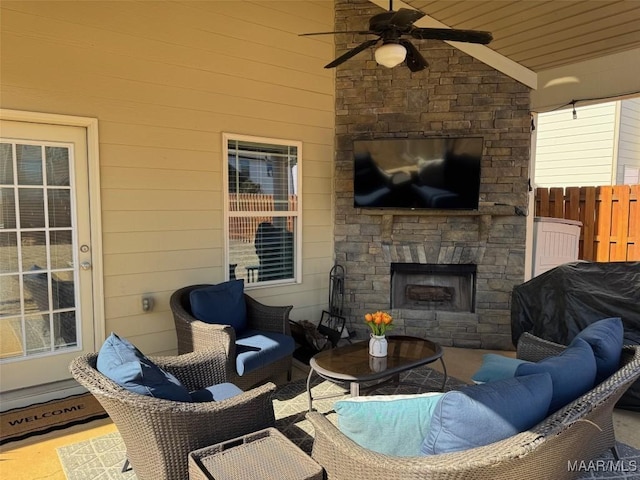 view of patio / terrace with a ceiling fan, fence, and an outdoor living space with a fireplace