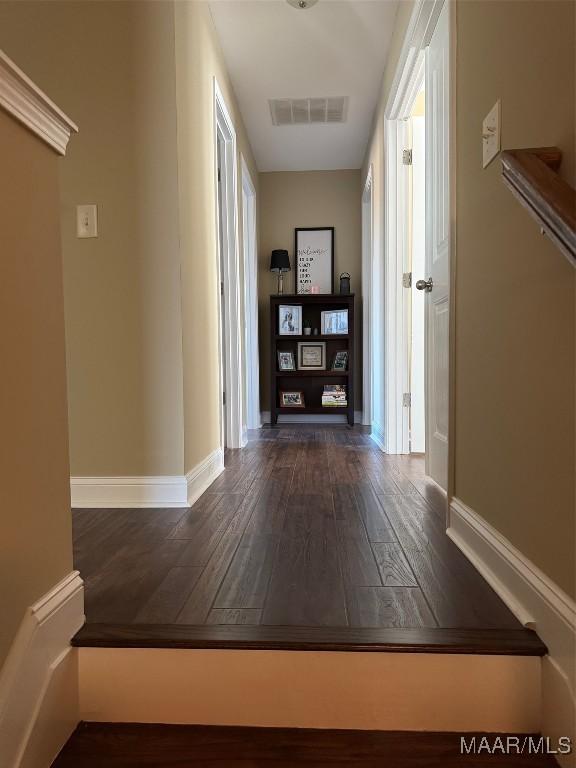 hallway with baseboards, visible vents, and hardwood / wood-style floors