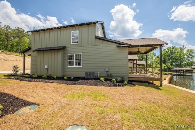 back of property featuring central AC, a lawn, board and batten siding, and a wooden deck