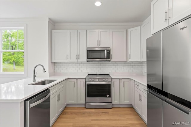 kitchen with stainless steel appliances, tasteful backsplash, a sink, and light countertops