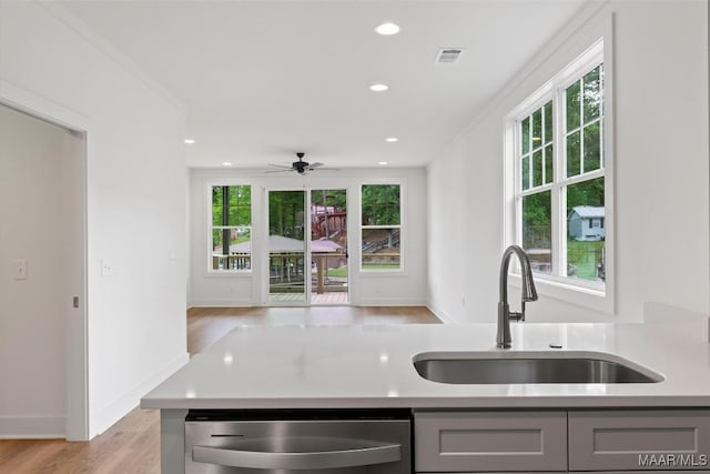 kitchen with gray cabinets, light countertops, a sink, and dishwasher