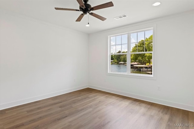 unfurnished room featuring ornamental molding, wood finished floors, visible vents, and baseboards