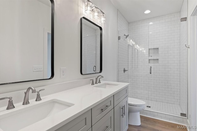 bathroom with a stall shower, a sink, toilet, and wood finished floors