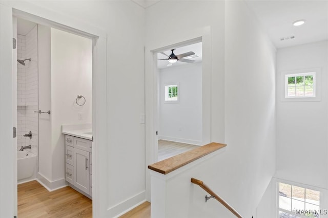 bathroom featuring baseboards, visible vents, wood finished floors, bathtub / shower combination, and vanity