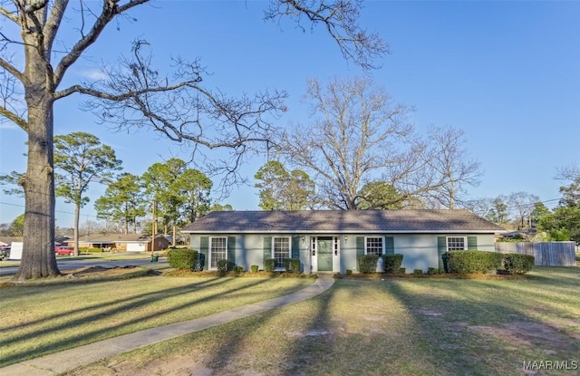 ranch-style house featuring fence, a front lawn, and stucco siding