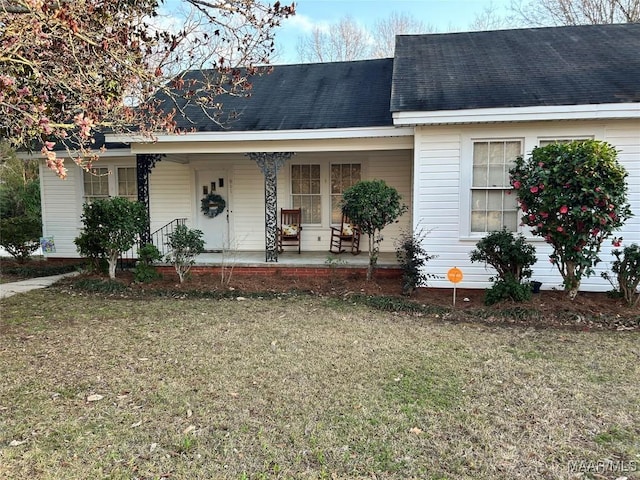 view of front facade with a porch, a front yard, and a shingled roof