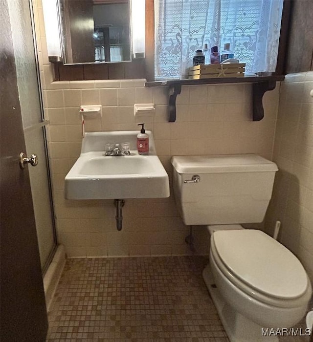 911 W Tuskeena St, Wetumpka, AL 36092 - bathroom with toilet, tile walls, a sink, and a shower stall