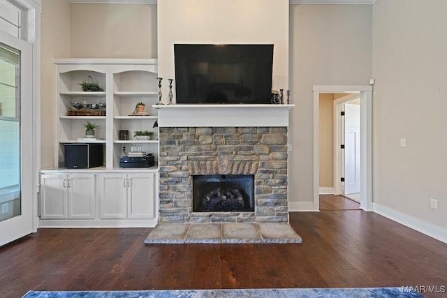 unfurnished living room with dark wood-style flooring, a fireplace, and baseboards