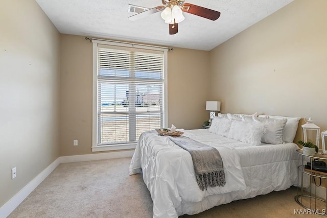 bedroom featuring carpet floors, a ceiling fan, baseboards, and a textured ceiling