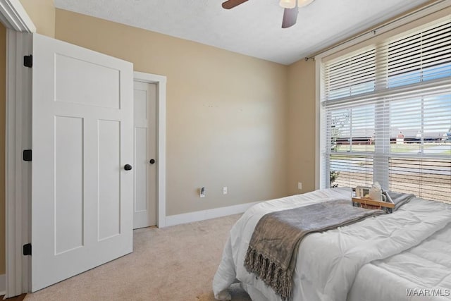 bedroom featuring a ceiling fan, light colored carpet, and baseboards