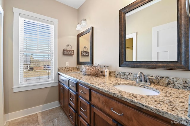 full bath with double vanity, tile patterned flooring, baseboards, and a sink