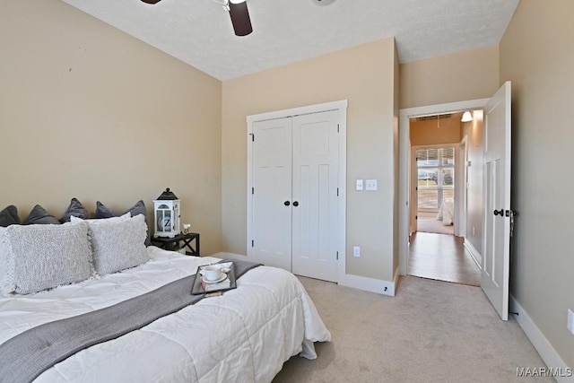 bedroom with ceiling fan, light colored carpet, baseboards, a closet, and attic access