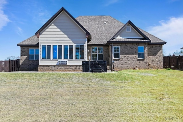 rear view of house with brick siding, a lawn, a shingled roof, and fence