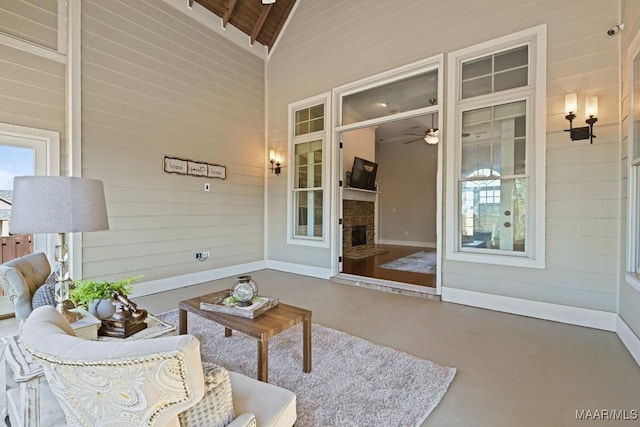 exterior space with wooden walls, ceiling fan, wood ceiling, concrete flooring, and a fireplace