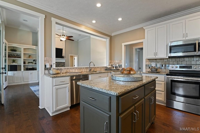 kitchen featuring stainless steel appliances, a center island, white cabinets, and light stone counters