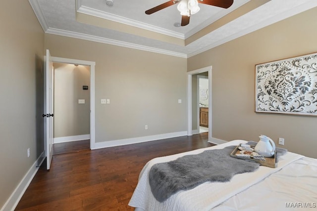 bedroom with baseboards, a tray ceiling, wood finished floors, and ornamental molding