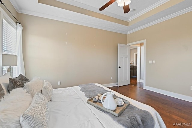 bedroom with ornamental molding, a tray ceiling, wood finished floors, and baseboards