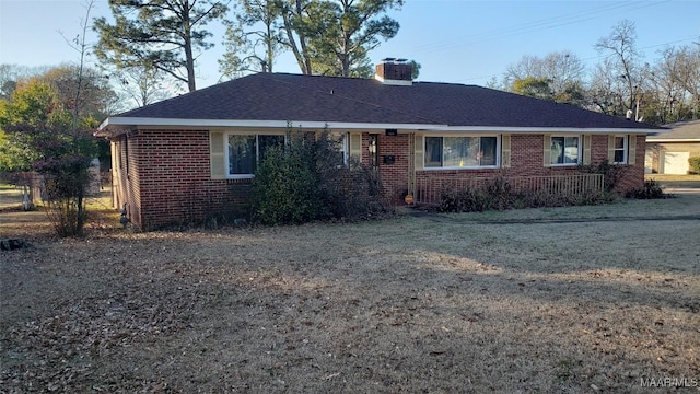 ranch-style home featuring roof with shingles, a chimney, and brick siding