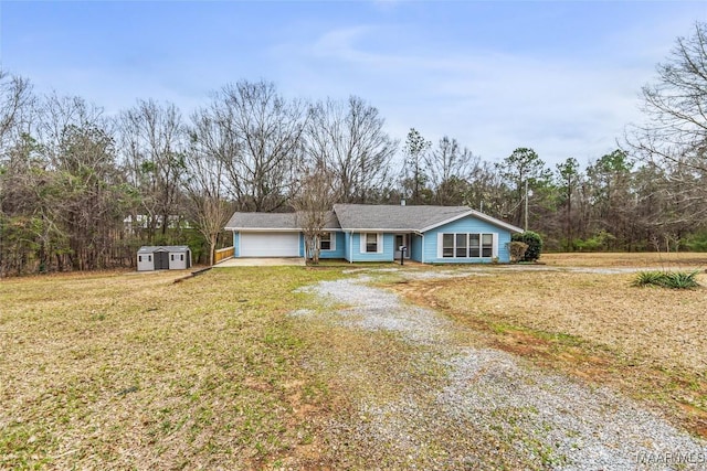 ranch-style house featuring driveway, a garage, an outbuilding, a storage unit, and a front lawn