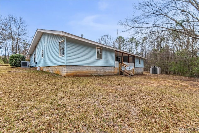 view of front facade with a storage shed, central AC, a front lawn, and an outdoor structure