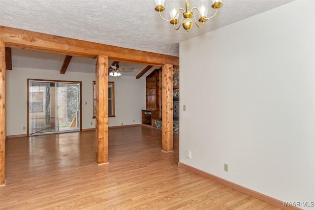 empty room featuring a textured ceiling, ceiling fan with notable chandelier, light wood-type flooring, and baseboards