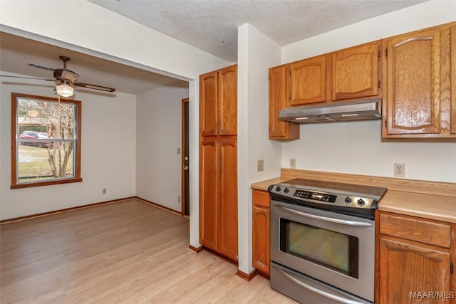 kitchen featuring under cabinet range hood, light countertops, stainless steel electric range, brown cabinets, and light wood finished floors