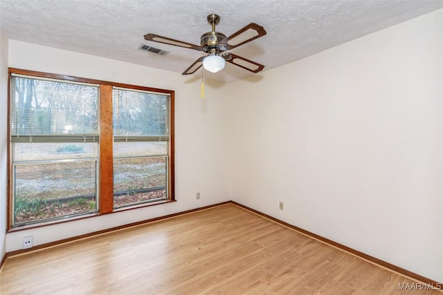 unfurnished room featuring a wealth of natural light, visible vents, and light wood-style floors