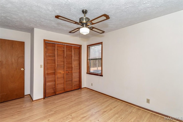 unfurnished bedroom featuring light wood-style floors, a closet, a textured ceiling, and baseboards