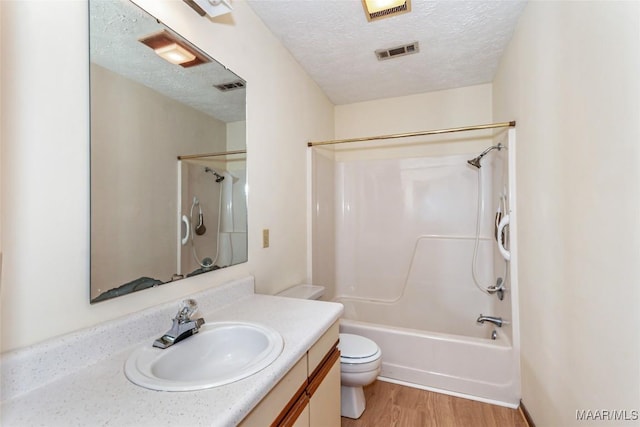 bathroom with visible vents, toilet, wood finished floors, a textured ceiling, and vanity