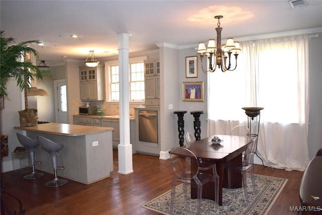 dining space featuring decorative columns, ornamental molding, dark wood finished floors, and visible vents