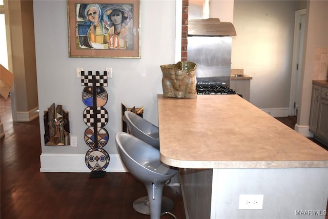 kitchen featuring light countertops, extractor fan, wood finished floors, and baseboards