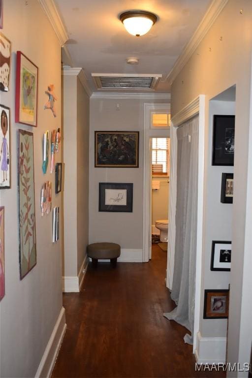 hall featuring baseboards, visible vents, dark wood-type flooring, and ornamental molding