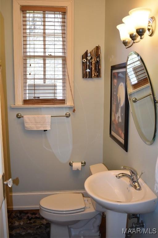 half bath featuring a sink, toilet, and baseboards