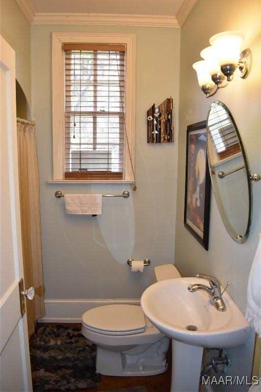 bathroom featuring toilet, a shower with shower curtain, a sink, baseboards, and ornamental molding