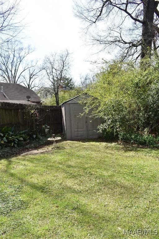 view of yard with fence, a storage unit, and an outbuilding