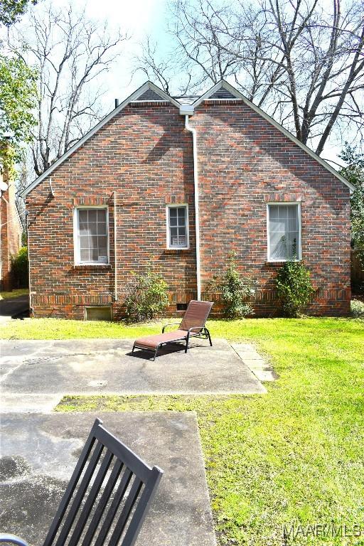 exterior space featuring a patio area, a yard, and brick siding