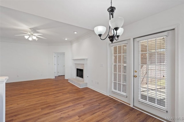 unfurnished living room featuring a fireplace with raised hearth, ornamental molding, wood finished floors, and baseboards