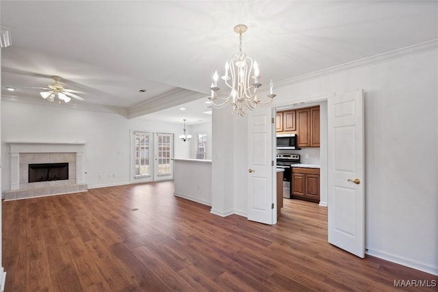 unfurnished living room featuring dark wood-type flooring, a tile fireplace, crown molding, and ceiling fan with notable chandelier