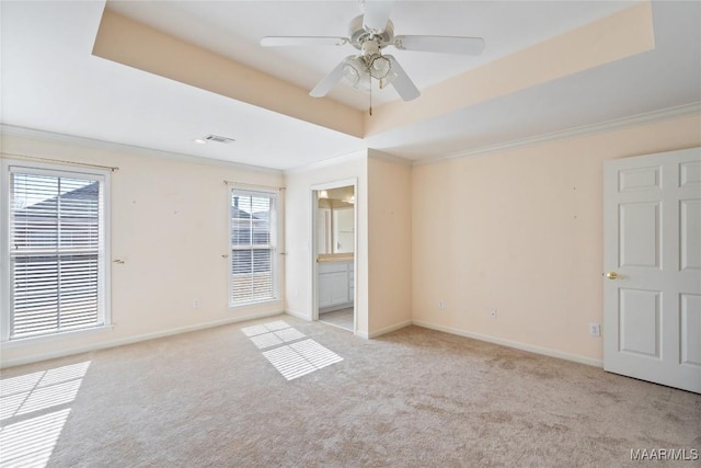 unfurnished bedroom with a tray ceiling, crown molding, visible vents, light carpet, and baseboards