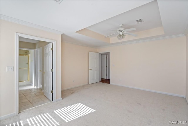 unfurnished room with carpet, a raised ceiling, visible vents, and crown molding