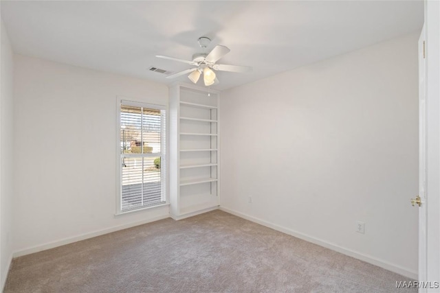 spare room featuring ceiling fan, carpet, visible vents, and baseboards