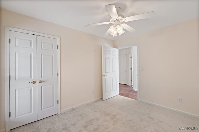 unfurnished bedroom with ceiling fan, carpet floors, a closet, and baseboards