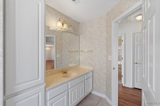 bathroom featuring vanity, baseboards, and wallpapered walls