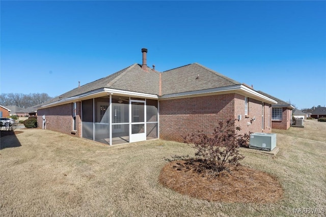 back of property featuring brick siding, a lawn, central AC unit, and a sunroom