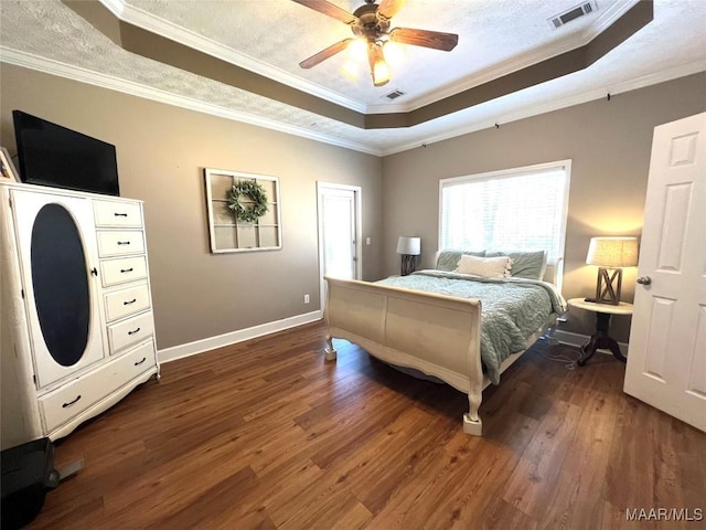 bedroom featuring ornamental molding, a tray ceiling, visible vents, and dark wood finished floors