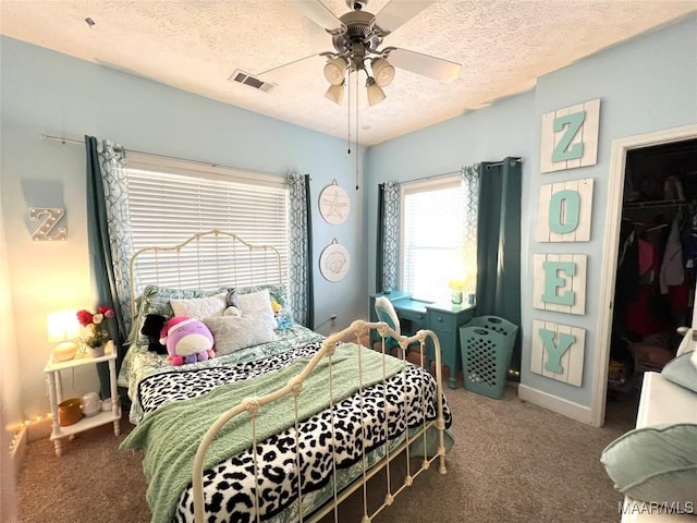 carpeted bedroom with a closet, visible vents, a spacious closet, a ceiling fan, and a textured ceiling