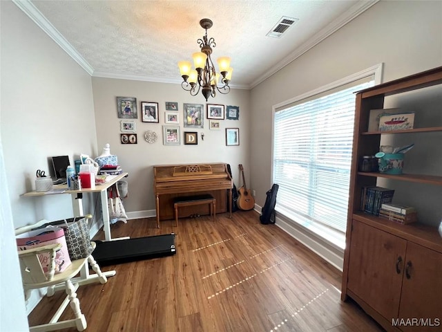 interior space with a textured ceiling, wood finished floors, visible vents, and crown molding